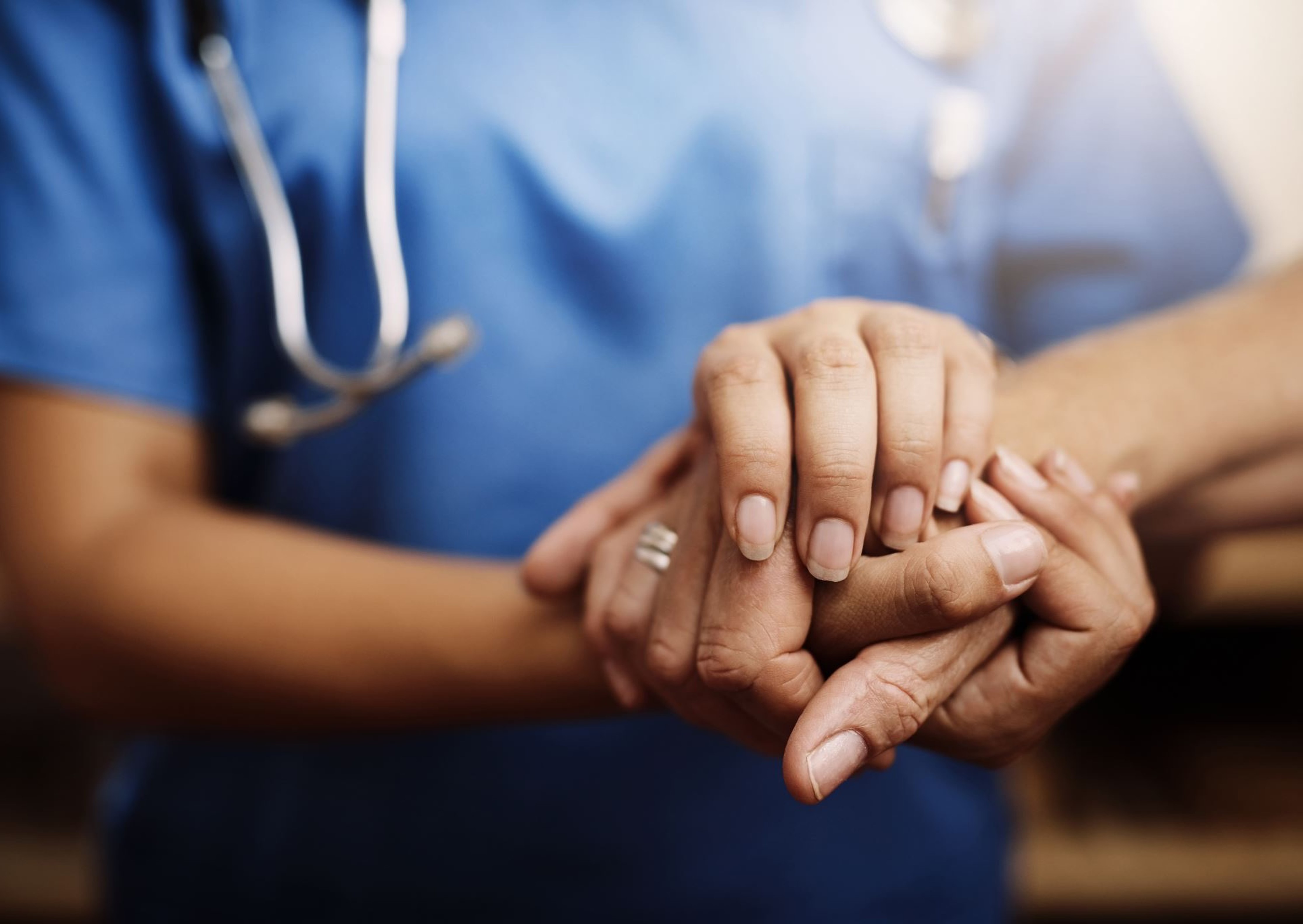 A nurse holding a patient&rsquo;s hands