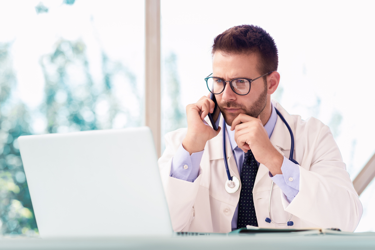 Physician on the phone while checking a laptop